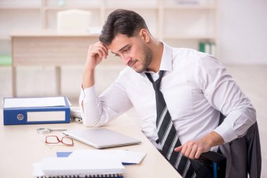 Genç işadamı işyerinde oturuyor.