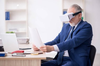 Old businessman employee wearing virtual glasses in the office