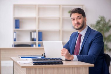 Genç işadamı işyerinde oturuyor.