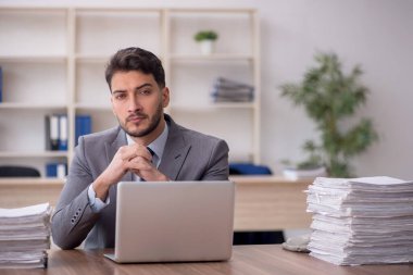 Young employee and too much work at workplace