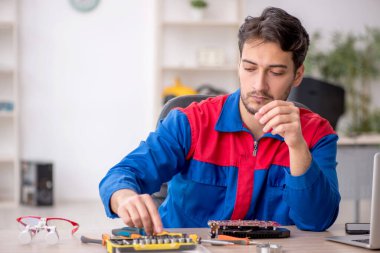 Laboratuvarda bilgisayar tamir eden genç bir tamirci.