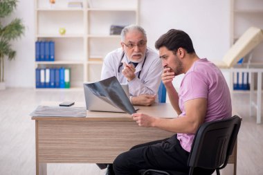 Genç hasta yaşlı doktoru ziyaret ediyor.