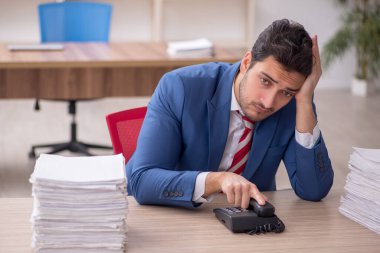 Genç işadamı ve işyerinde çok fazla iş var.