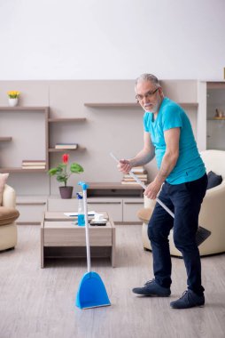 Yaşlı müteahhit evi temizliyor.