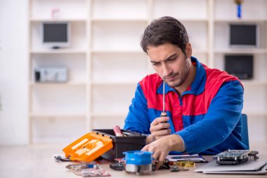 Atölyede bilgisayar tamir eden genç bir tamirci.