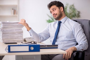 Young employee and too much work at workplace