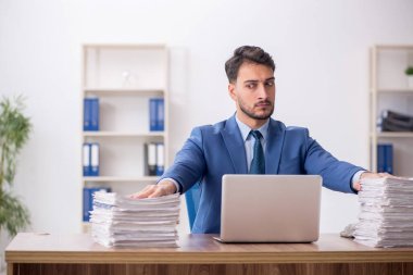 Young employee and too much work at workplace