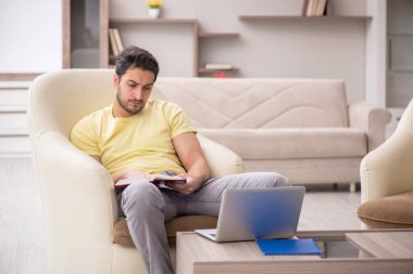 Genç erkek öğrenci salgın sırasında evden çalışıyor.