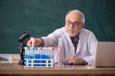 Old teacher chemist sitting in the classroom