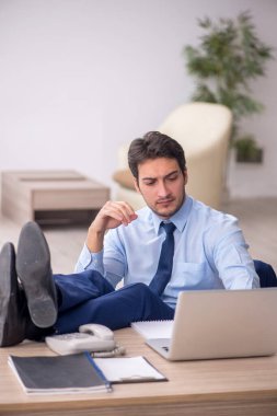 Genç işadamı işyerinde oturuyor.