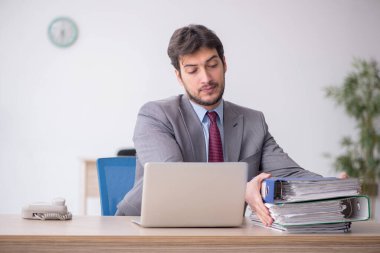 Young employee and too much work at workplace