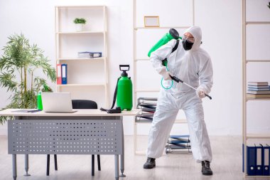 Young contractor disinfecting office during pandemic