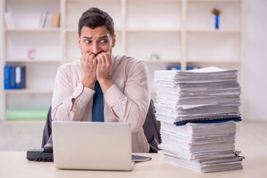 Young employee and too much work at workplace