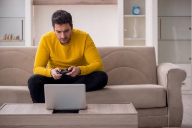 Evde video oyunu oynayan genç bir erkek öğrenci