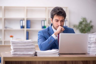 Young employee and too much work at workplace