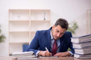 Young employee and too much work at workplace