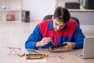 Laboratuvarda bilgisayar tamir eden genç bir tamirci.