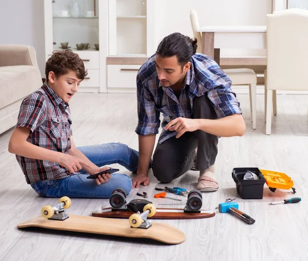 Jovem Pai Reparando Skate Com Seu Filho Casa — Fotografia de Stock