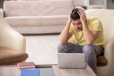 Genç erkek öğrenci salgın sırasında evden çalışıyor.