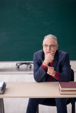 Old teacher sitting in the classroom