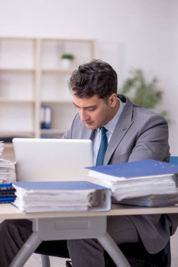Young employee and too much work at workplace