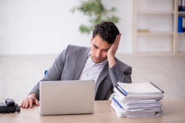 Young employee and too much work at workplace