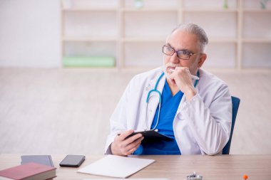 Old doctor sitting at the hospital