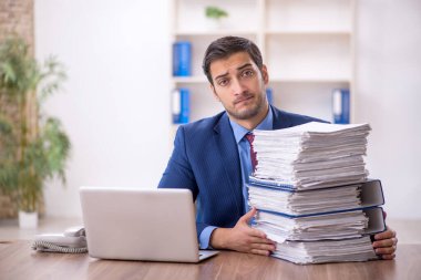 Genç işadamı ve işyerinde çok fazla iş var.
