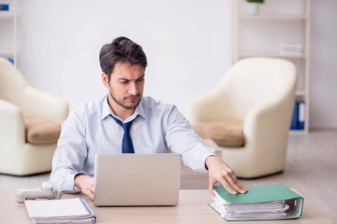 Genç işadamı işyerinde oturuyor.