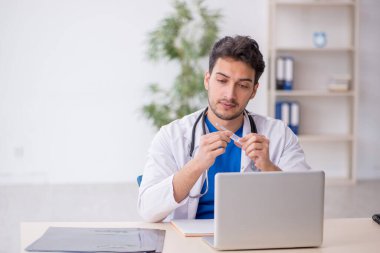 Genç doktor hastanede şırınga tutuyor.