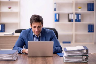 Genç bir erkek işçi ve işyerinde çok fazla iş var.