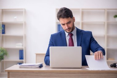 Genç işadamı işyerinde oturuyor.