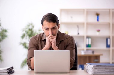 Genç erkek çalışan işyerinde oturuyor.