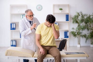 Genç hasta yaşlı doktoru ziyaret ediyor.