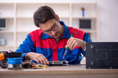 Atölyede bilgisayar tamir eden genç bir tamirci.