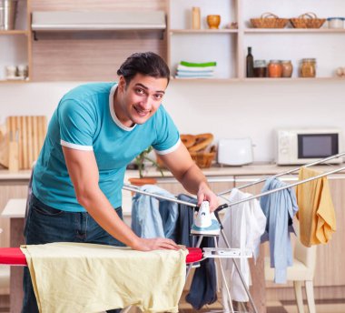 Genç adam evde ütü yapıyor.