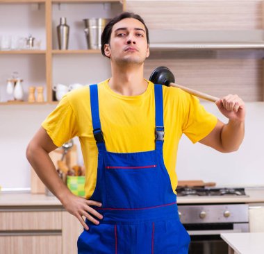 Genç erkek müteahhit evde musluğu tamir ediyor.