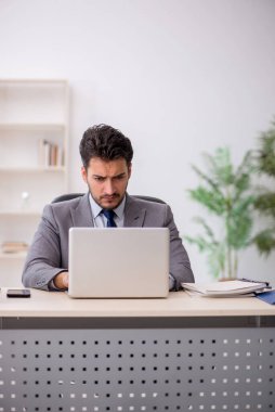 Young employee and too much work at workplace