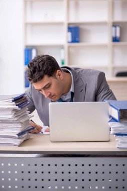 Young employee and too much work at workplace