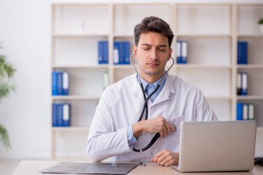 Klinikte steteskop tutan genç bir doktor.