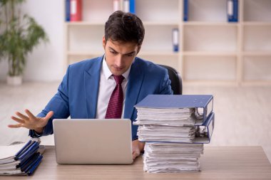 Genç işadamı ve işyerinde çok fazla iş var.