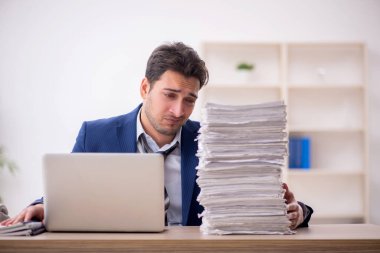 Young employee and too much work at workplace