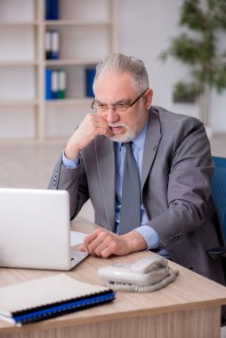 Old employee sitting at workplace