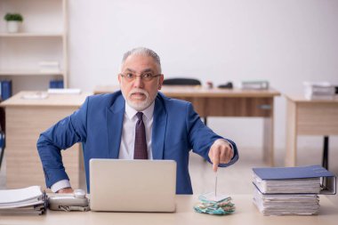 Old employee sitting at workplace