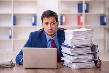 Genç işadamı ve işyerinde çok fazla iş var.