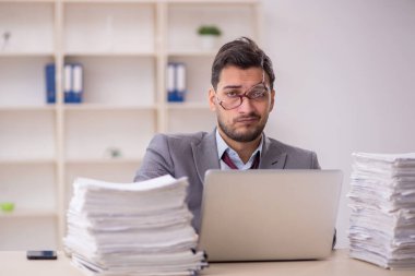 Young employee and too much work at workplace