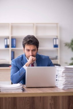 Young employee and too much work at workplace