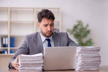 Young employee and too much work at workplace