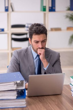 Young employee and too much work at workplace
