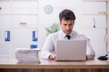 Young employee and too much work at workplace